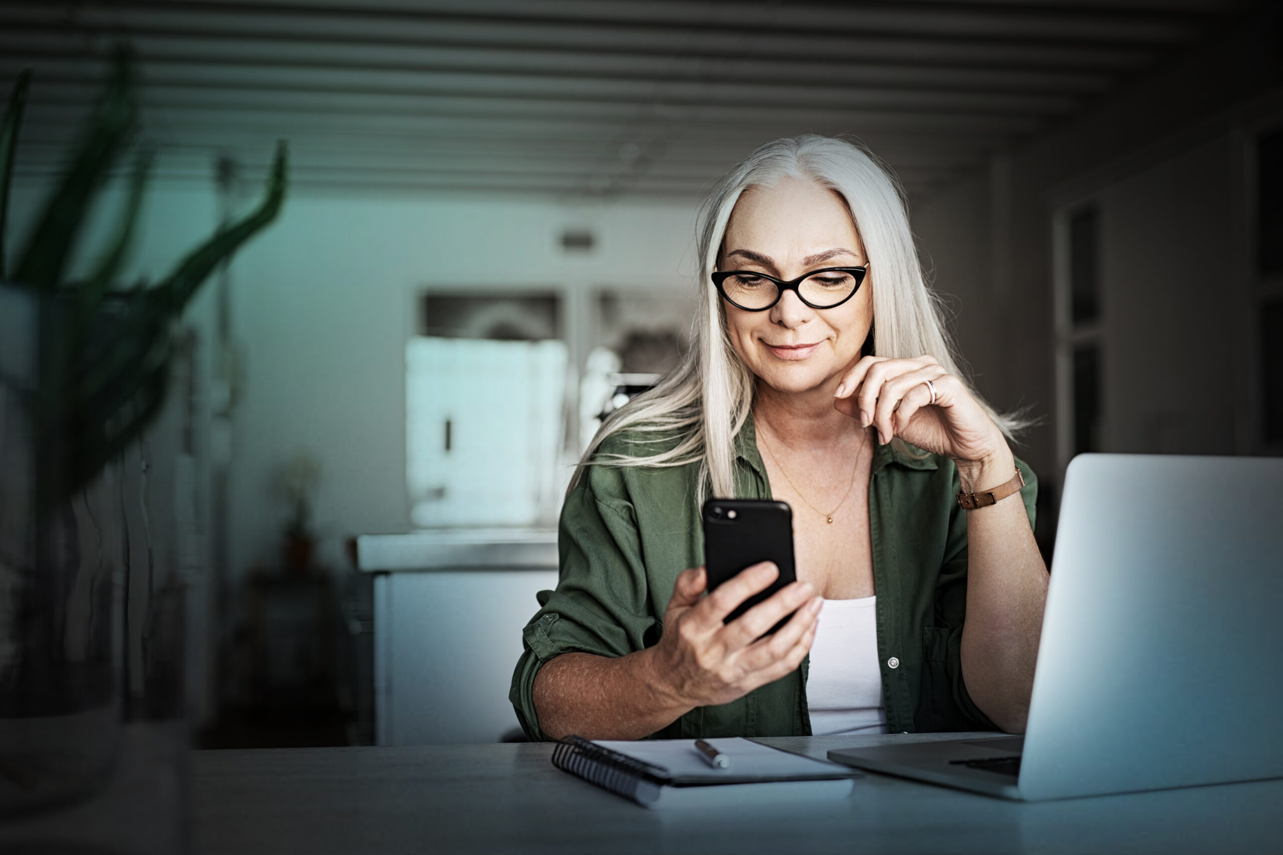 Happy,Senior,Woman,Using,Mobile,Phone,While,Working,At,Home